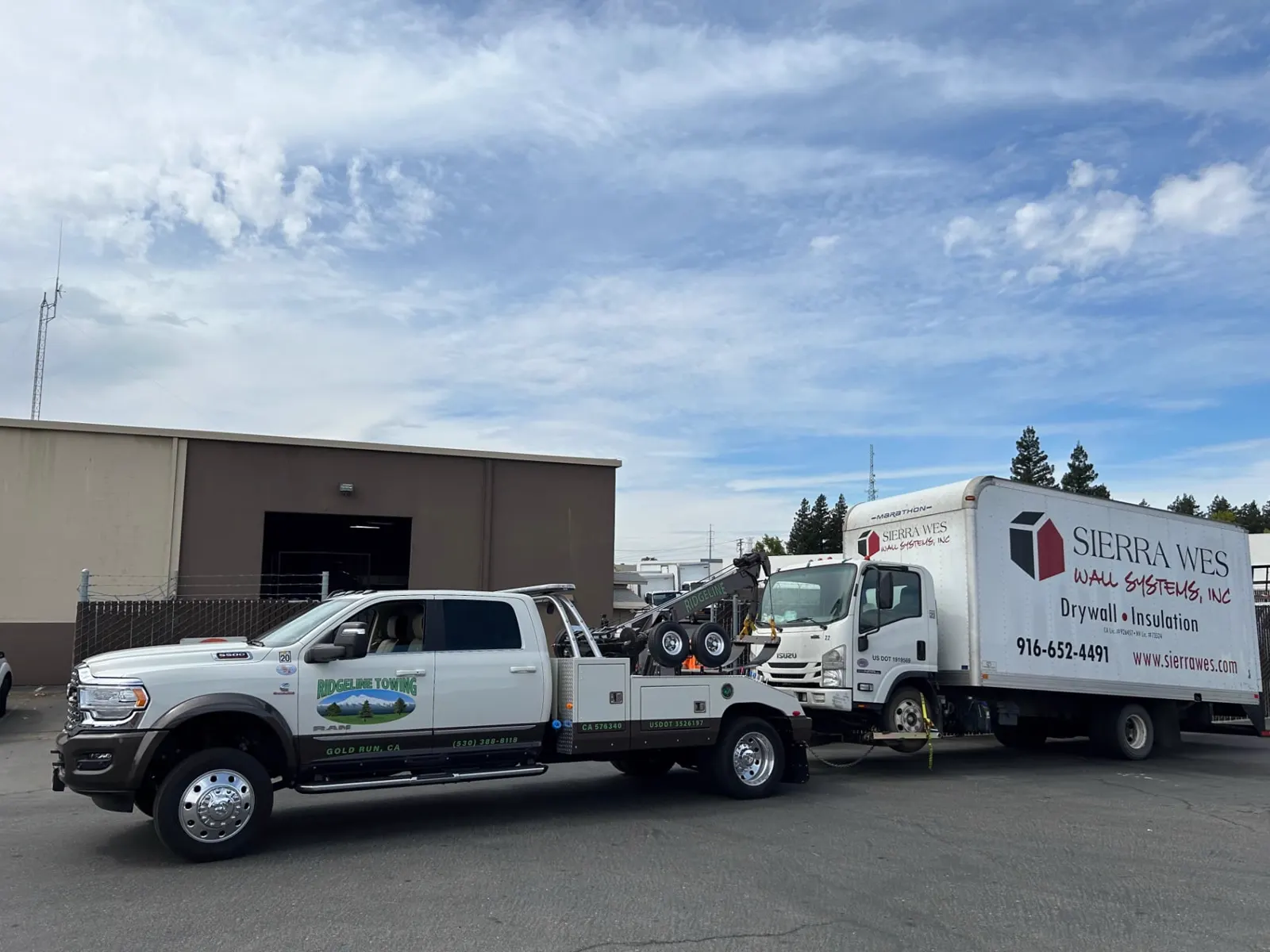 Ridgeline Towing wrecker towing a box truck with its wheel lift